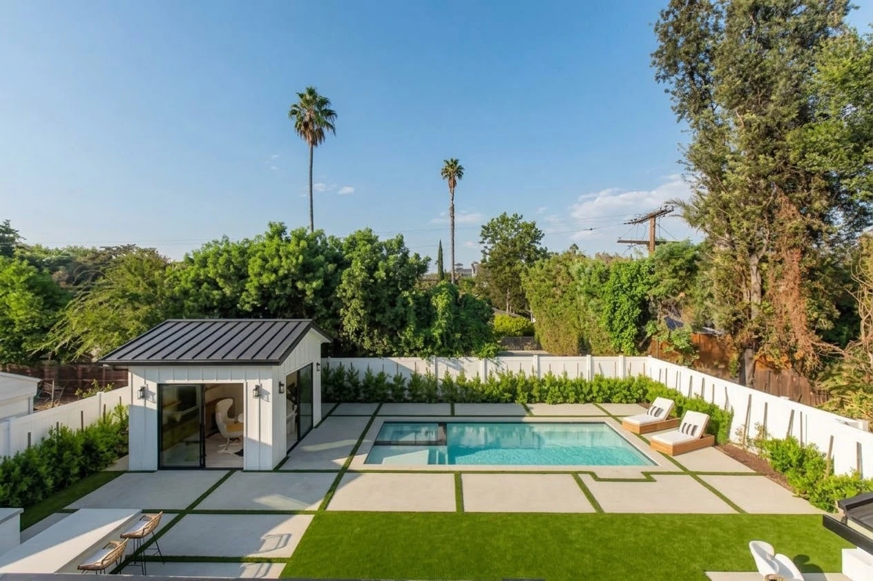 Pool and spa with a detached white pavilion, sun loungers and grass-lined concrete terraces