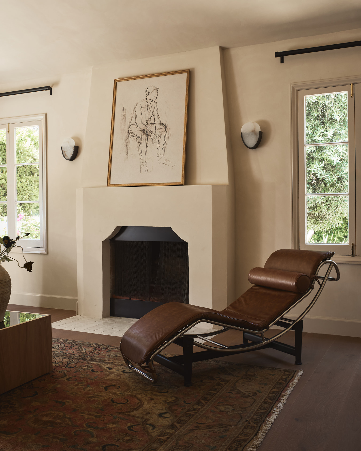 Plaster living room with arched fireplace, leather chaise and antique rug