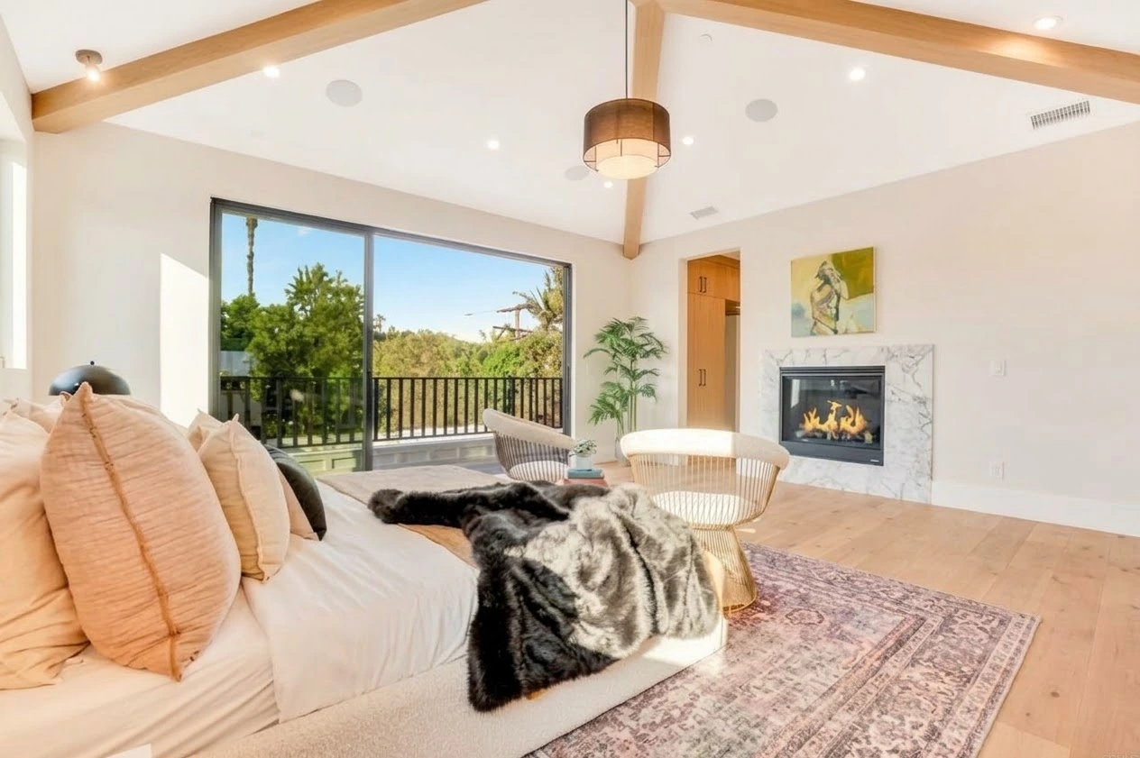 Primary suite with vaulted oak beams, a marble fireplace and sliding glass doors to a balcony