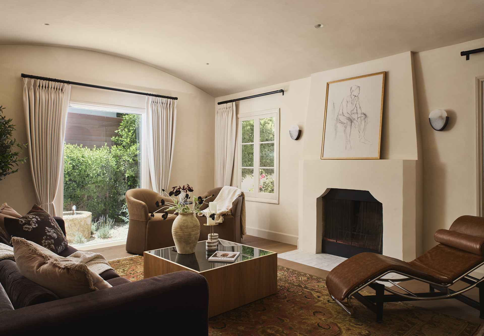Living room with barrel-vaulted ceiling, fireplace and swivel chairs facing the courtyard