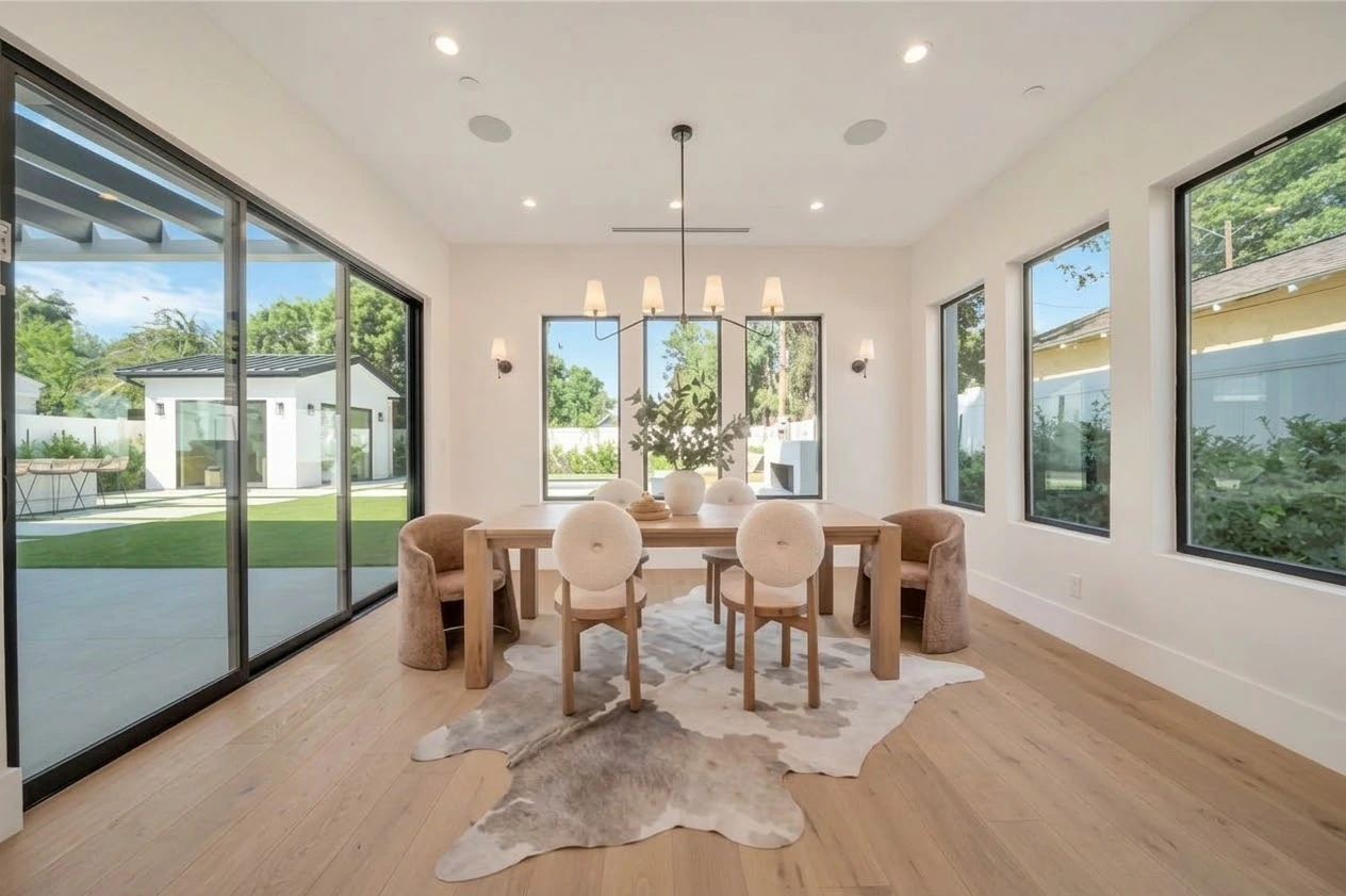 Sunlit dining room with oak floors, upholstered chairs and black-framed sliding doors to the garden