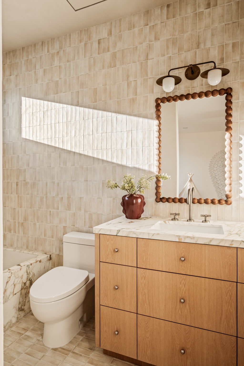 Bathroom with hand-glazed zellige tile, an oak vanity, marble counter and beaded wood mirror