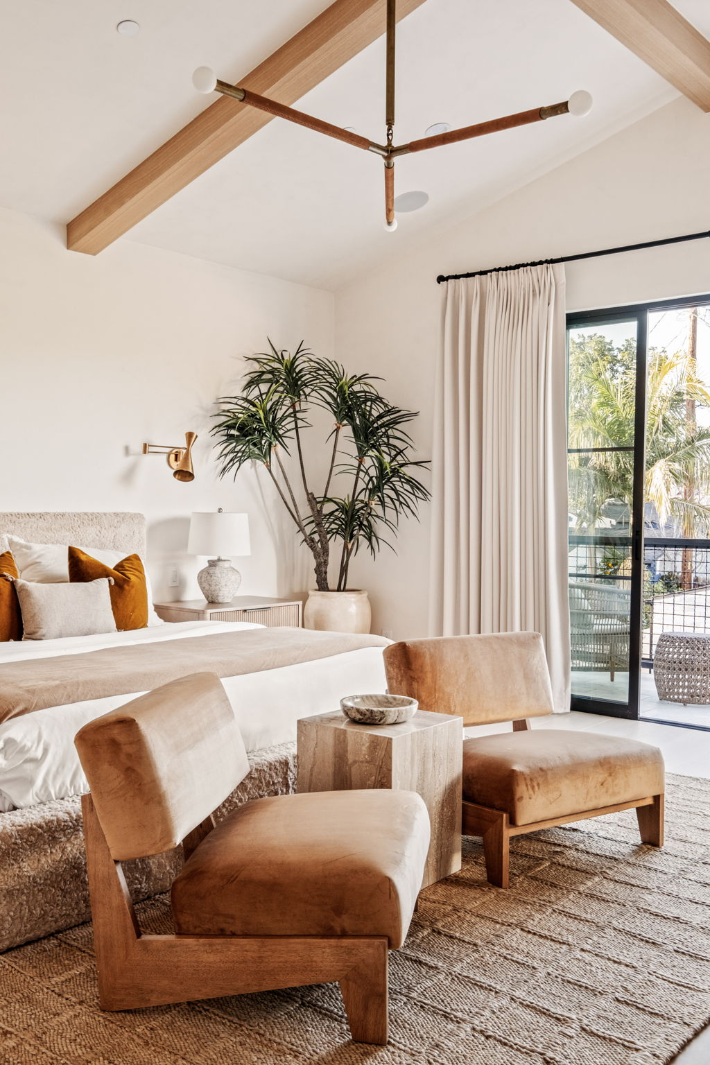 Primary bedroom with vaulted beamed ceiling, plaster walls and velvet lounge chairs