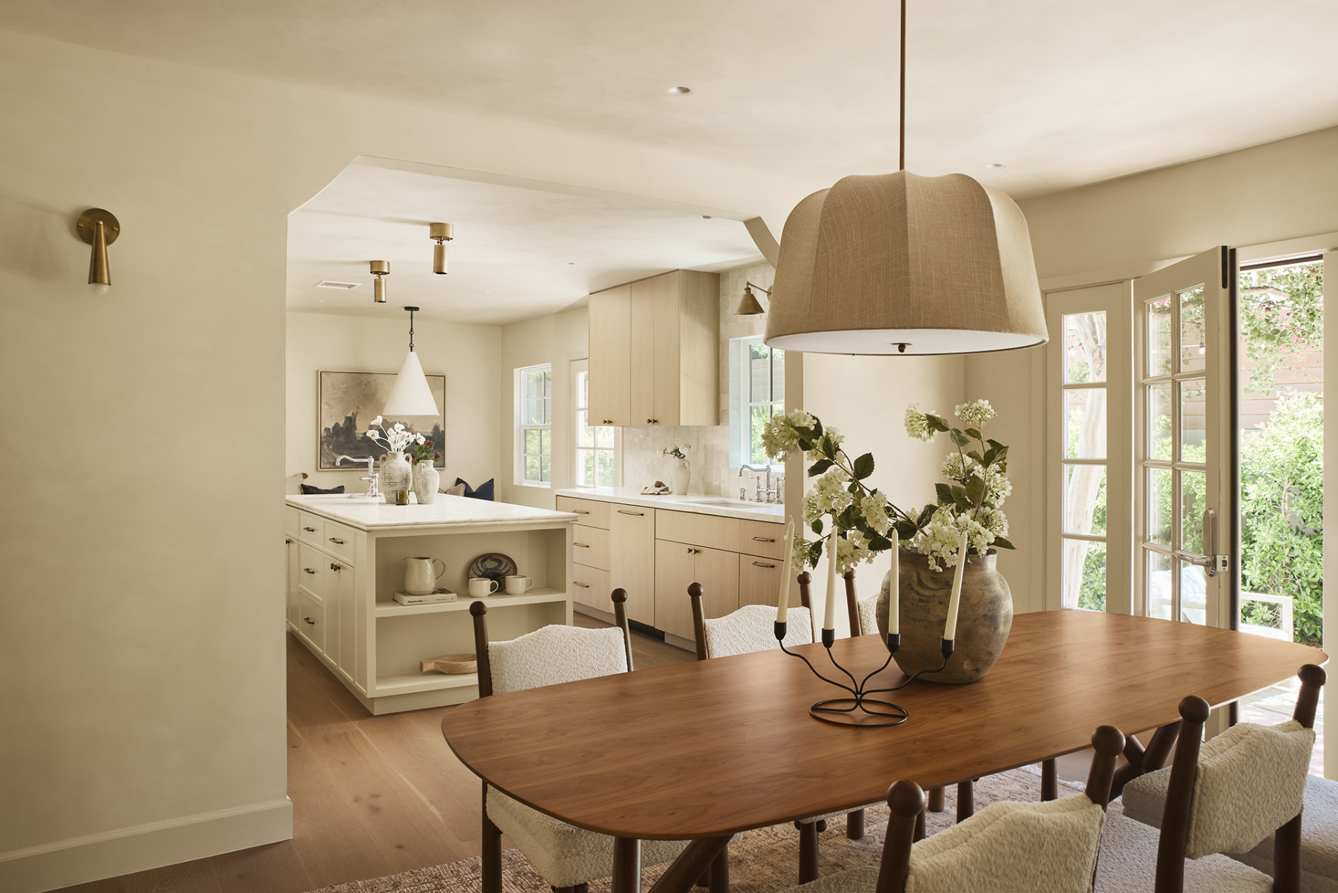 Open dining and kitchen with white oak cabinetry, marble island and linen dome pendant