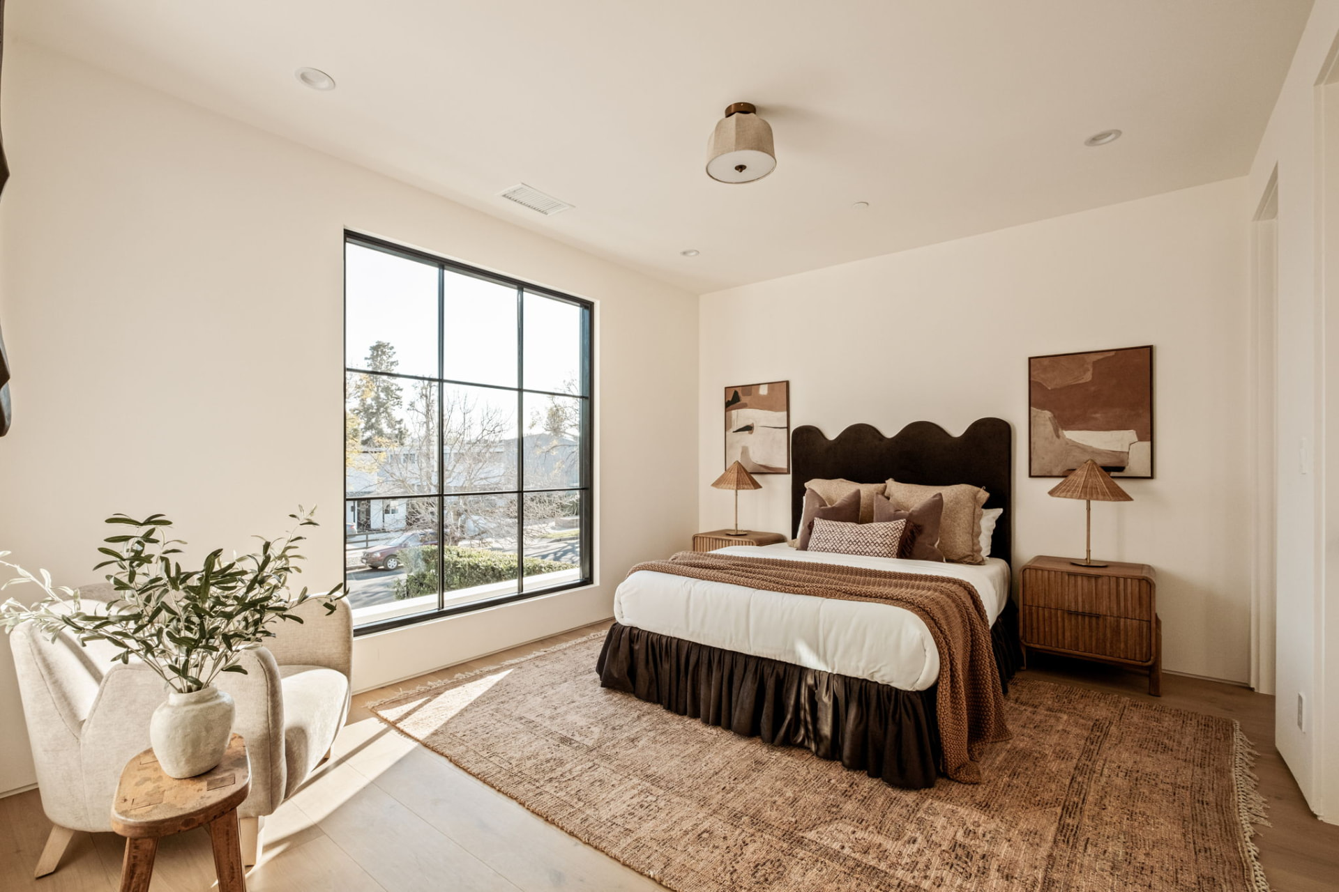 Guest bedroom with a scalloped headboard, fluted nightstands, rattan lamps and a jute rug