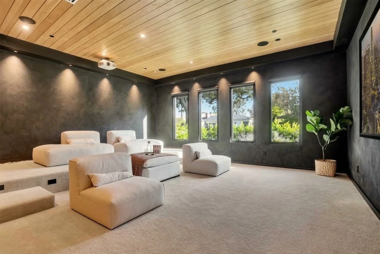 Media room seating with cream lounge chairs, dark textured walls, an oak ceiling and tall garden windows