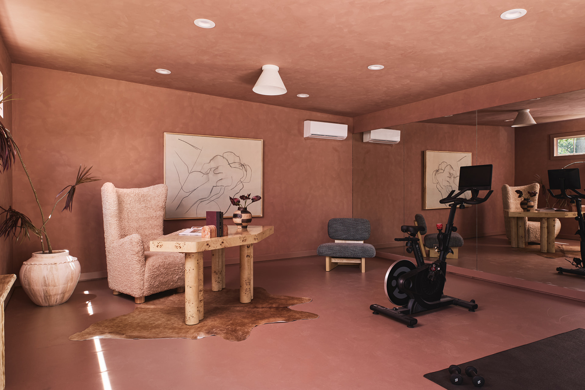 Terracotta limewash gym and studio with burl desk, sheepskin chair and mirrored wall