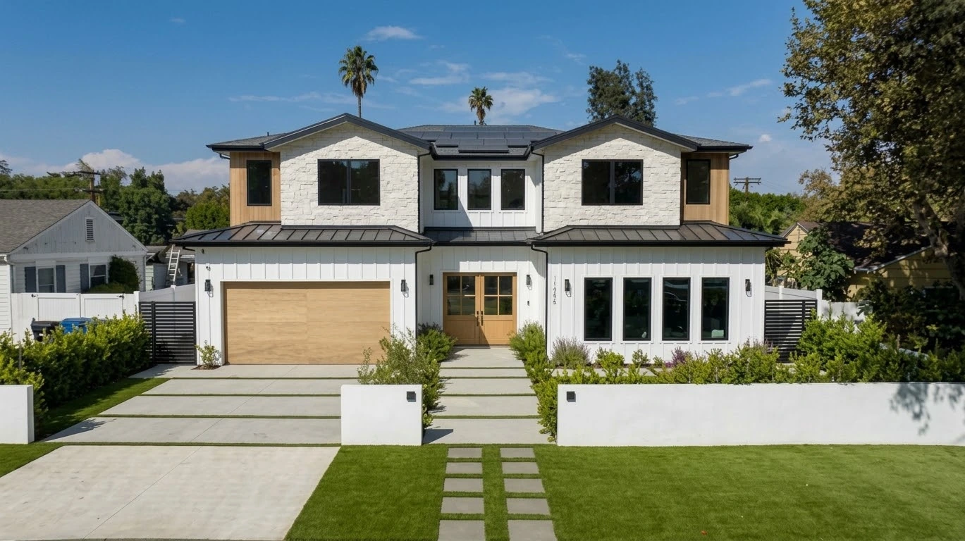 Front elevation in daylight with stone gables, white siding, solar panels and an oak garage door