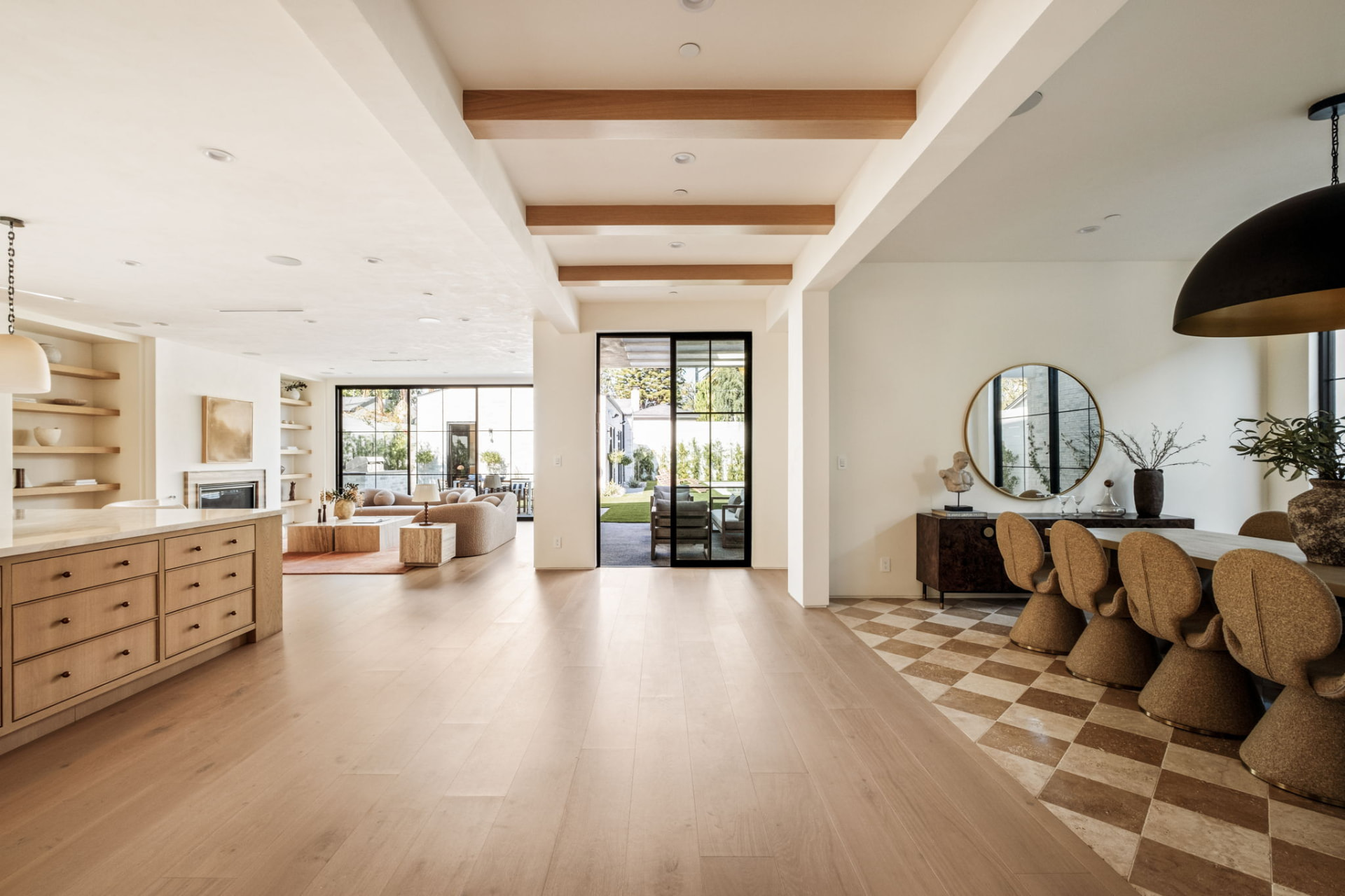 Wide open plan interior linking kitchen, living room and dining room with white oak floors and exposed beams