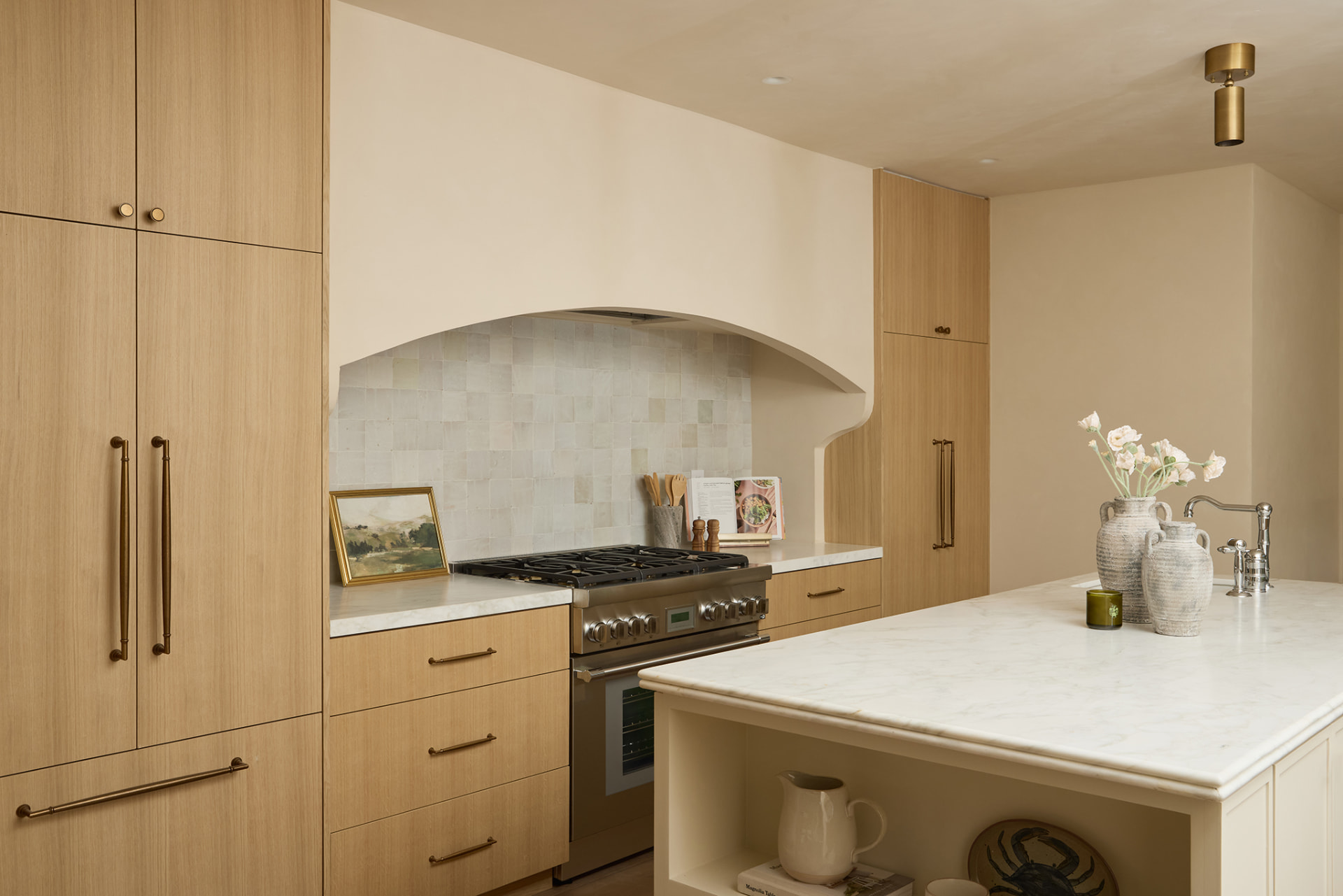 Oak kitchen with an arched plaster range niche, zellige backsplash and marble island