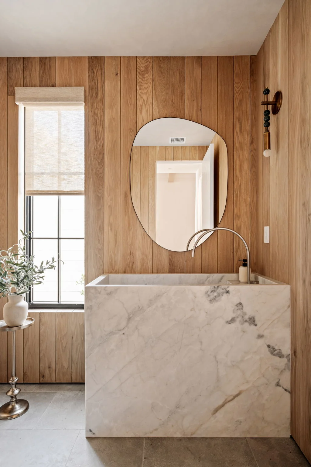 Powder room with white oak paneling, marble monolith sink and organic mirror
