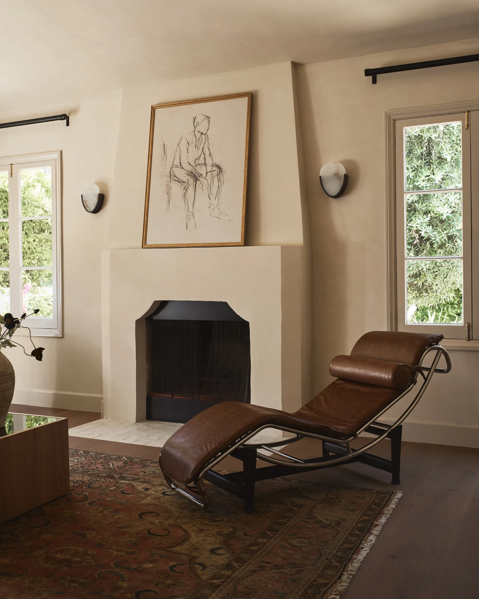 Plaster living room with arched fireplace, leather chaise and antique rug