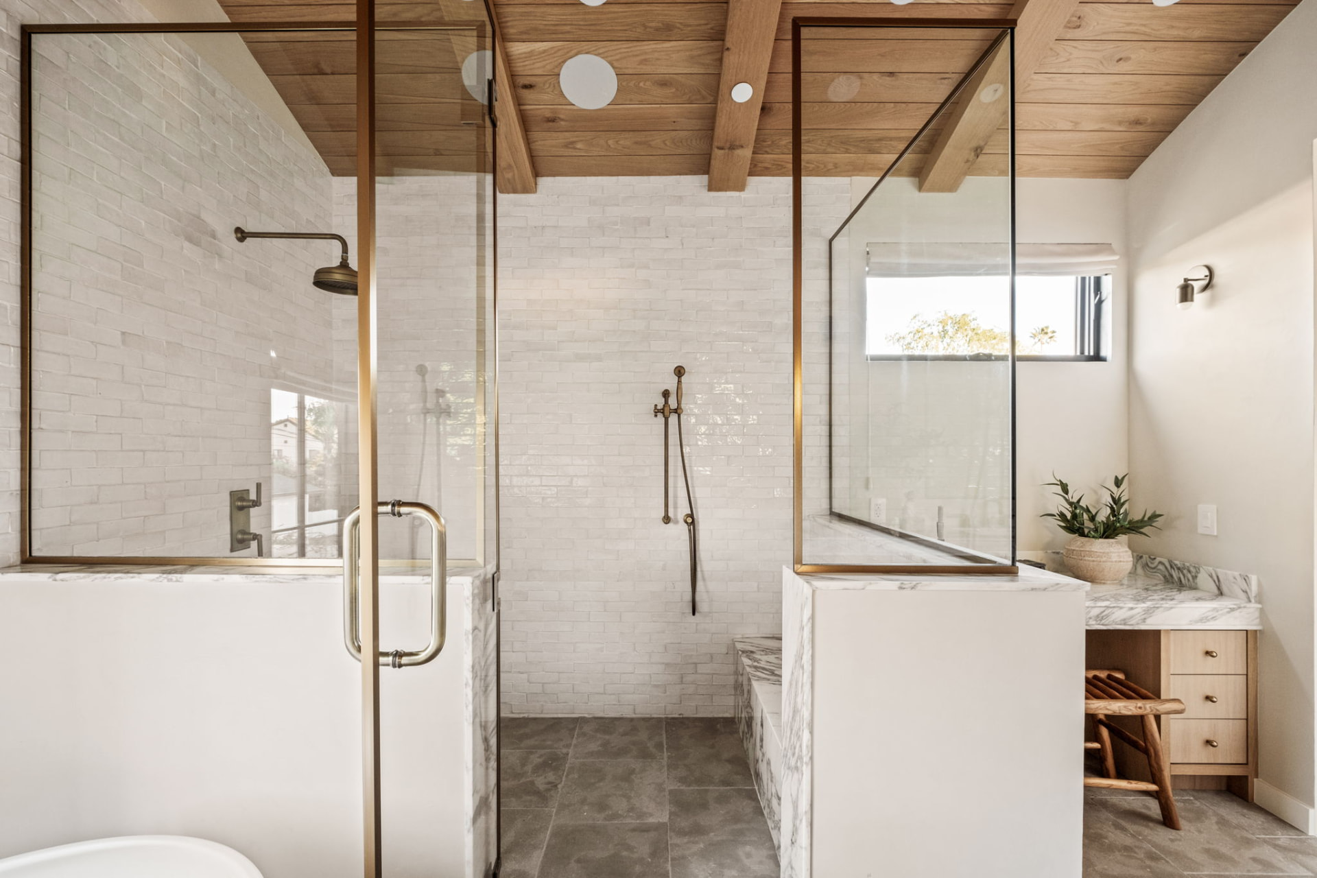 Walk-in shower with white brick tile, aged brass fittings and marble half-walls