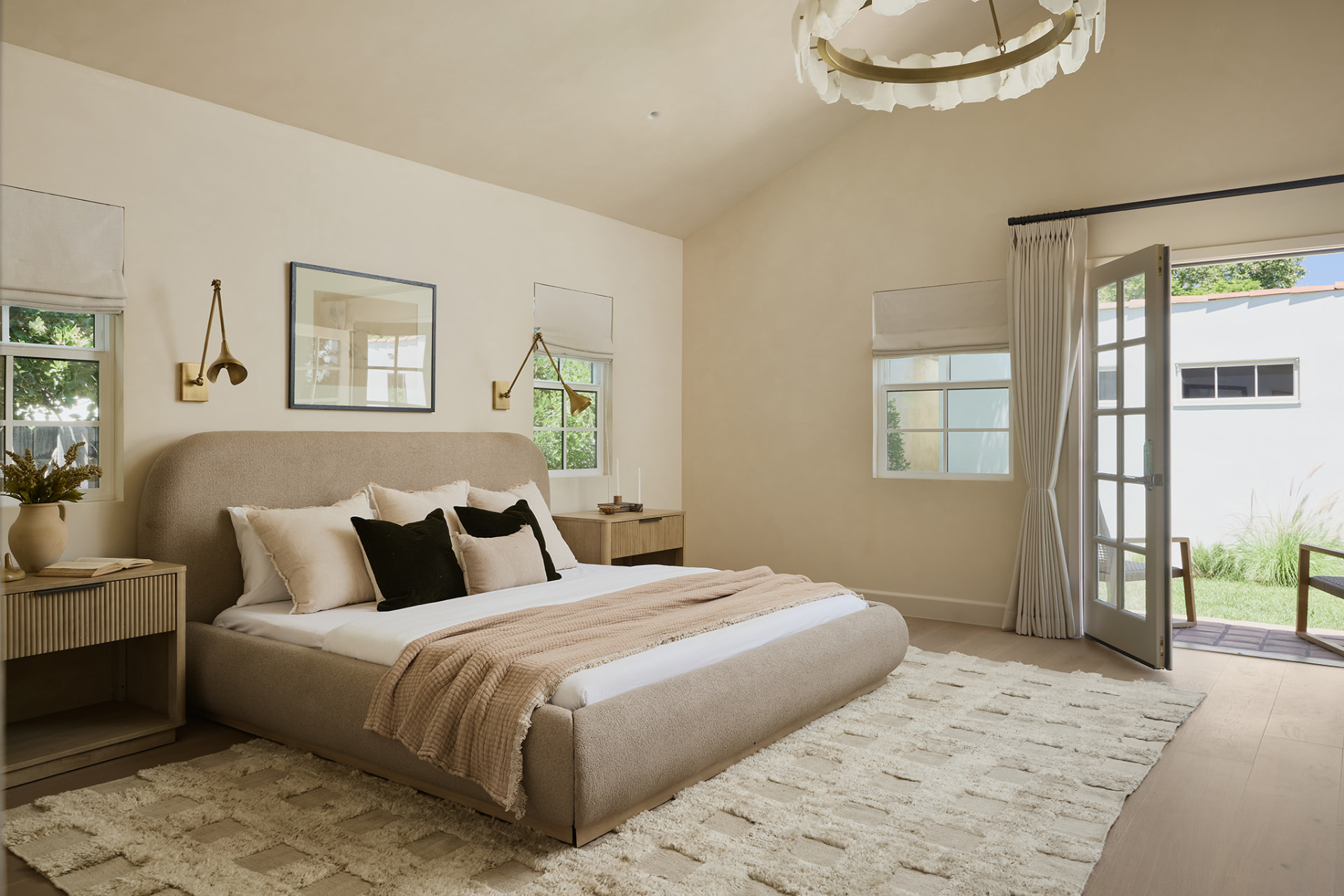 Primary suite with a vaulted ceiling, alabaster chandelier and French doors to the garden