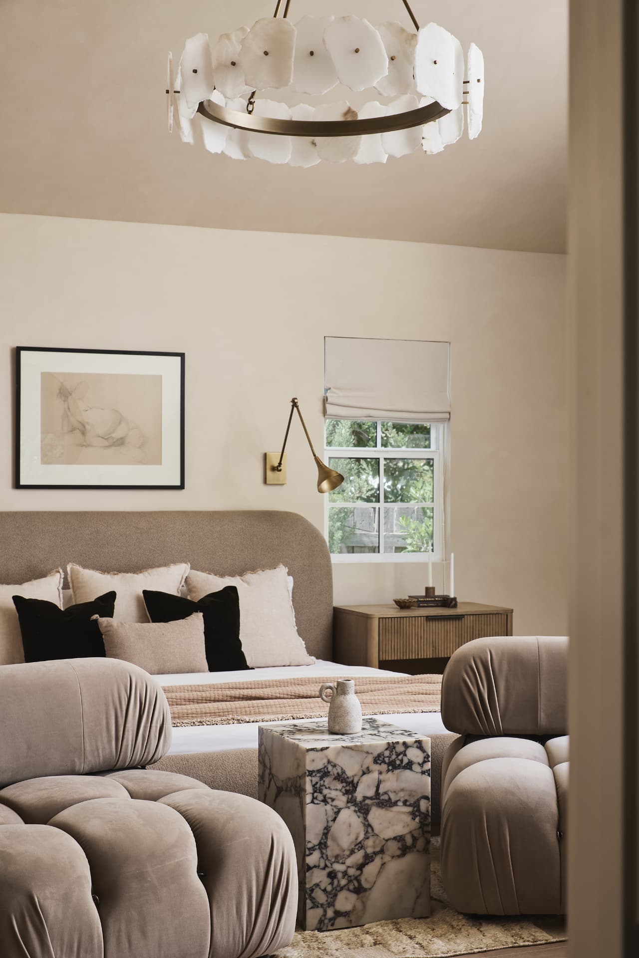 Living room with a curved sectional, alabaster chandelier and garden windows